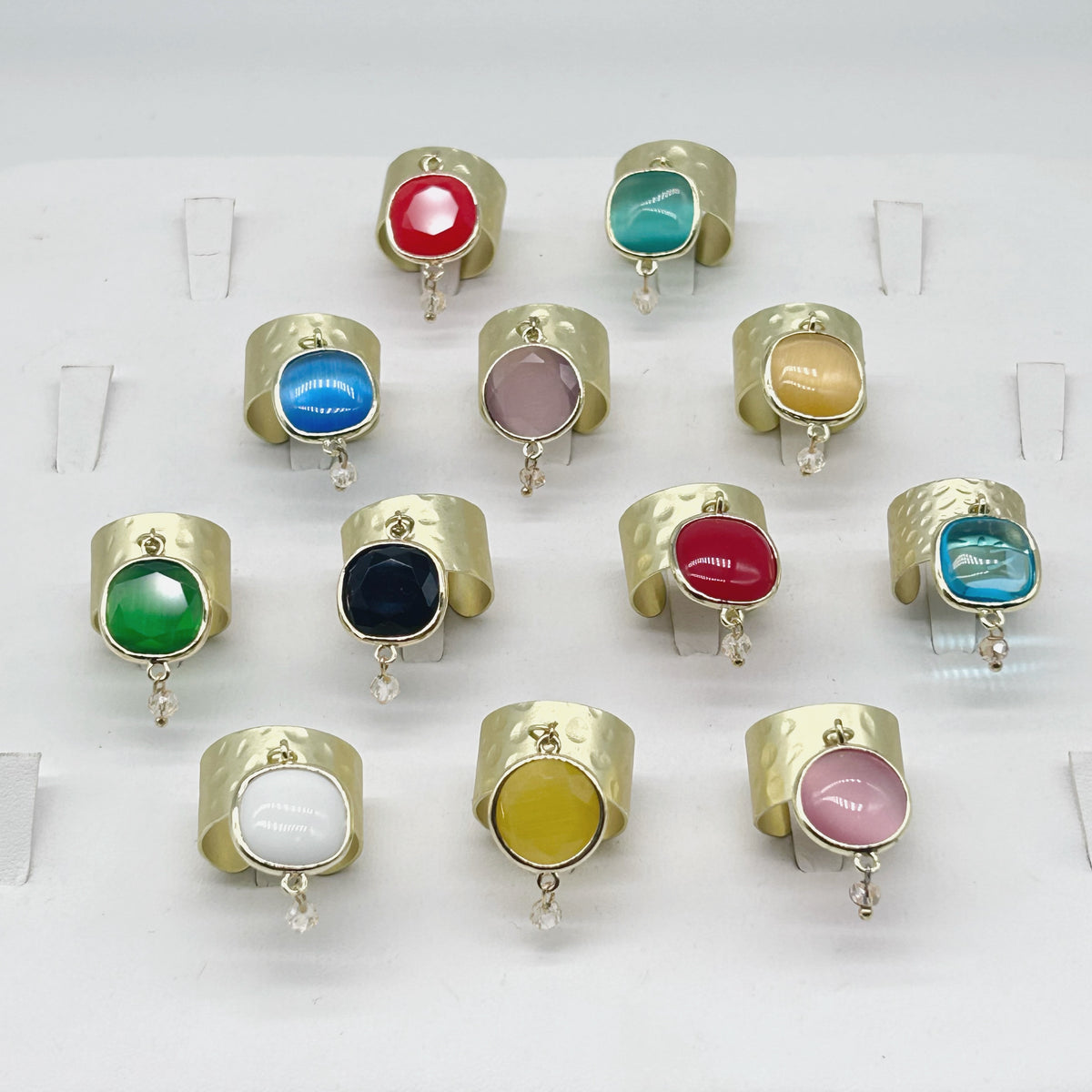 Anelli Fru fru a fascia larga in ottone satinato martellato con ciondoli mobili in pietra dura di vari colori e cristallo color champagne